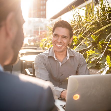 Man with laptop smiling in garden