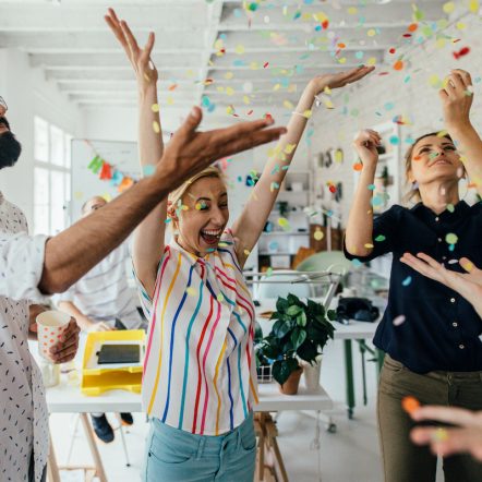 Photo of a group of coworkers having a happy occasion and celebrating together in their office