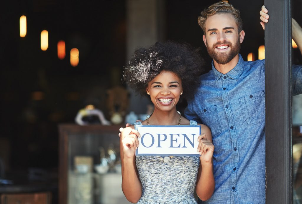 A couple holding an open sign.