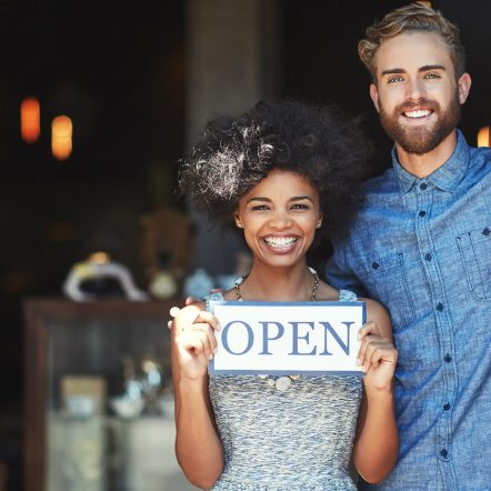A couple holding an open sign.