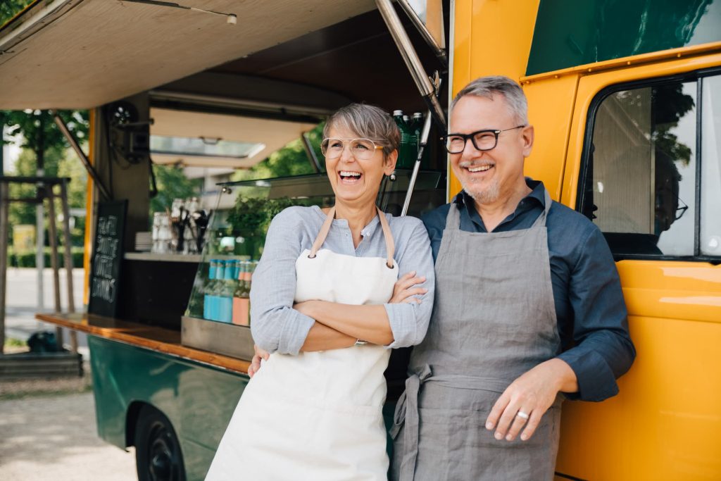 Two senior food truck owners laughing